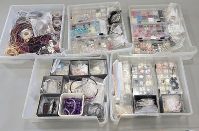 a lot of beads and jewelry in the bins on the table