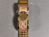 a close up of a gold watch on a gray surface
