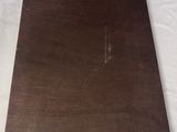 a wooden plaque on a white sheet with a tag on it