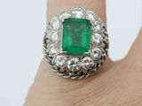 an image of a woman ' s hand holding an emerald and diamond ring
