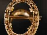 gros plan d'une broche en or sur une surface noire