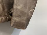 the back of a brown leather jacket hanging on a white wall