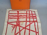 une boîte orange ornée d'un motif rouge et un tissu blanc avec un motif rouge