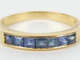 a close up of a yellow gold ring with blue sapphires