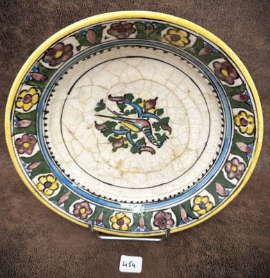 une assiette colorée ornée d'un oiseau, posée sur une table