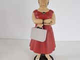 figurine représentant une femme en robe rouge avec une valise