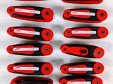 six pinces rouges et noires sont alignées sur une surface blanche