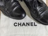 chanel black leather oxford shoes with laces on top of a white bag
