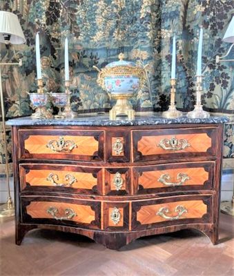 une commode dans une pièce, avec un mur tapissé derrière elle
