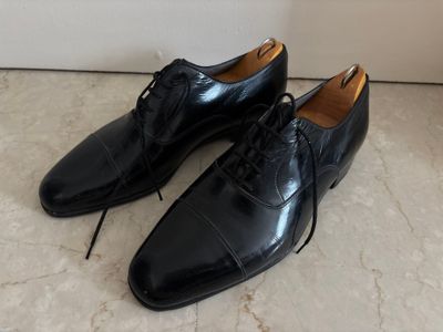chaussures en cuir noir à lacets pour homme, posées sur un sol en marbre