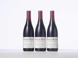 three bottles of red wine sitting on top of a table