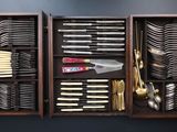 many different types of knives and spoons in a wooden box
