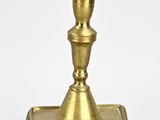 brass candle holder on a white surface with a white background