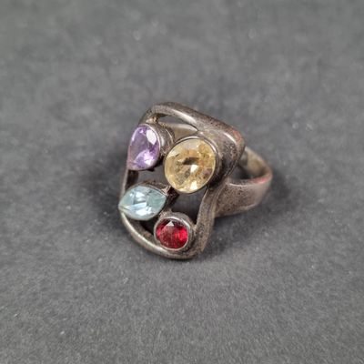 un gros plan d'une bague en argent sertie de pierres multicolores