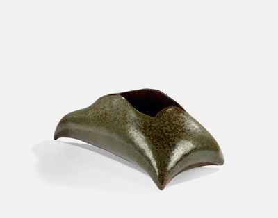 une image représentant un vase vert posé sur une surface blanche