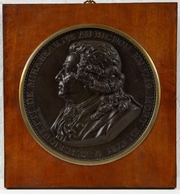 un gros plan d'une médaille posée sur une plaque en bois, sur fond blanc