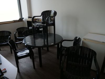 des chaises et une table dans une pièce dotée d'une fenêtre et d'un ordinateur portable