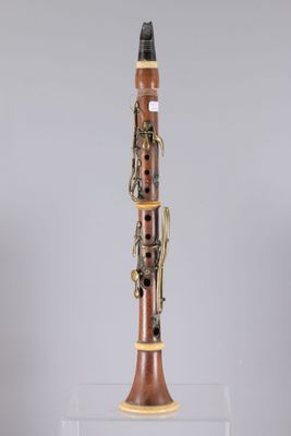 a clarinet with a wooden body and brass parts on a clear stand