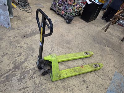 un chariot élévateur vert posé à même le sol dans un entrepôt