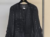 black jacket hanging on a hanger in front of a yellow wall