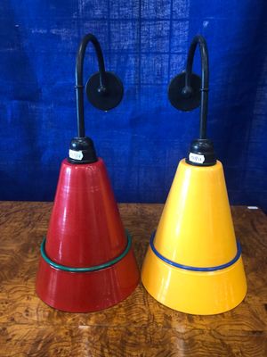 une paire de lampes coniques rouges, jaunes et bleues posées sur une table en bois