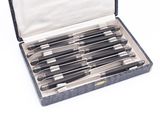 six black and silver pens in a case on a white surface