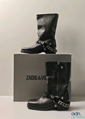 deux paires de bottes noires ornées de chaînes, posées sur une boîte