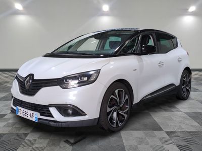 une voiture blanche est garée dans une grande pièce au sol en damier
