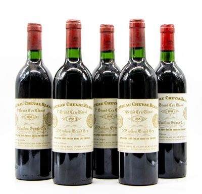 quatre bouteilles de vin rouge sont alignées sur une surface blanche