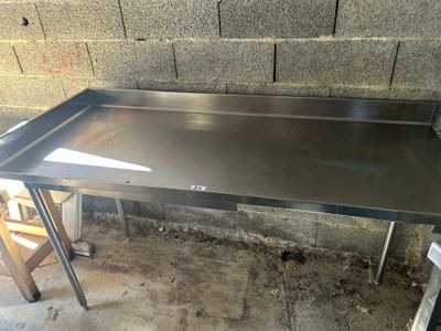 une table en acier inoxydable avec un plateau et des pieds en métal