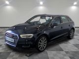 Une Audi noire est garée sur un sol à damier dans un garage