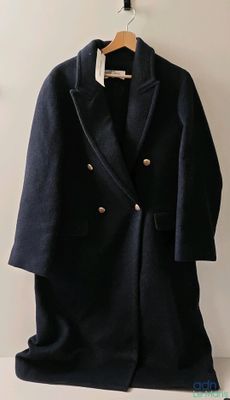 un manteau accroché au mur à côté de vêtements sur des cintres