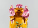 a yellow vase with a pink flower on it