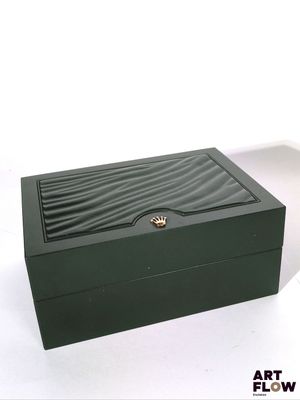 une boîte verte avec un couvercle noir posée sur une surface blanche