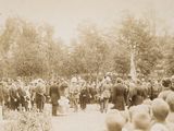 a crowd of people standing around a statue in the middle of a park