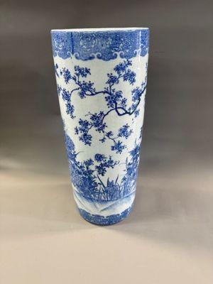tall blue and white vase with trees and flowers on it