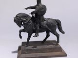 une statue représentant un homme à cheval, posée sur un socle en bois
