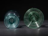 two green glass cups sitting on a black surface