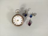 une petite montre de poche et une paire de boucles d'oreilles posées sur une table