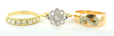trois bagues en or et en argent, ornées de diamants, posées sur un fond blanc