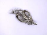 a silver brooch on a white surface with a white background