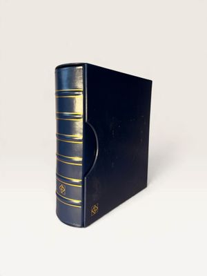 an old black book sitting on top of a white table