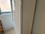 a white refrigerator in the corner of a room with a chair in front of it