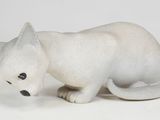 a small white cat figurine sitting on a white surface