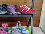 several pairs of children ' s shoes are on a shelf in a room
