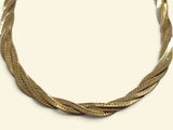 a gold necklace that is on display on a white surface