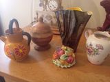 de nombreux vases de toutes sortes posés sur une table, avec une horloge en arrière-plan