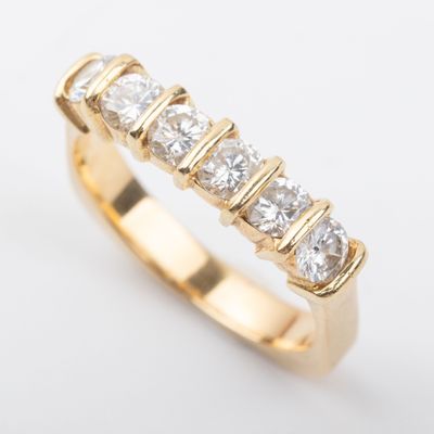 Gros plan sur une bague en or sertie de cinq diamants, sur fond blanc