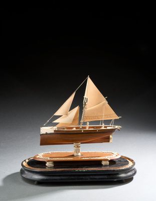 maquette en bois d'un voilier posée sur un socle, sur une surface blanche