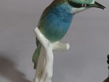 two figurines of birds sitting on a tree branch